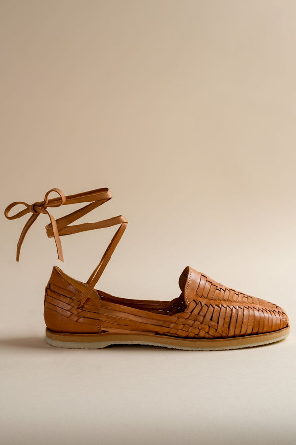 Brown woven shoe with ankle strap on a beige background