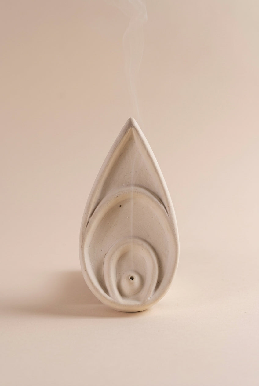 A white incense dish with a floral design, placed on a beige background.
